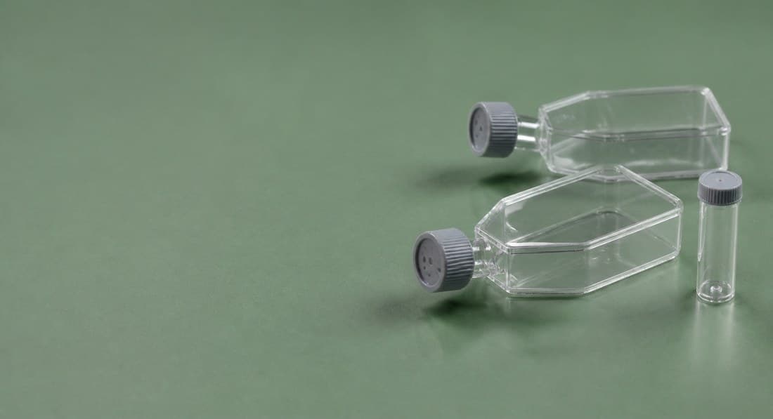 Two culture flasks on a green background