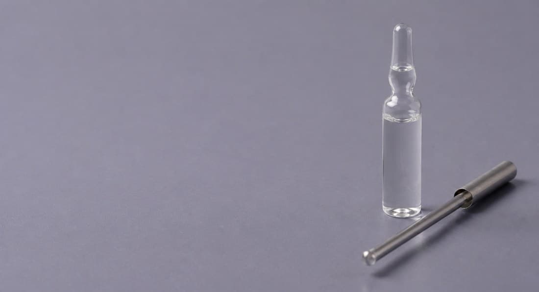 Ampoules and a metal sampling rod on a grey-purple background