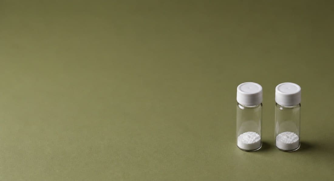 Two vials on an olive-green background